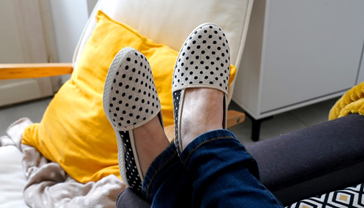 Femme portant jean et espadrilles blanches à pois bleu marine avec coussin jaune