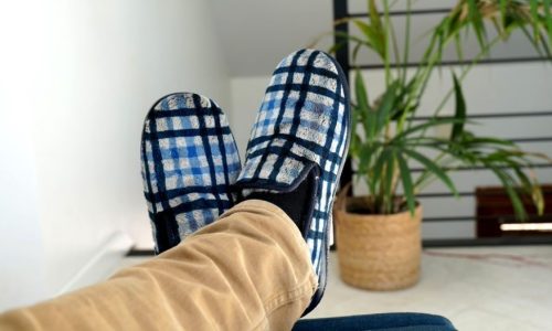 Chaussons-charentaises-homme-carreaux-bleu-airplum Homme allongé sur un canapé croisant les jambes avec charentaises à carreaux bleus aux pieds