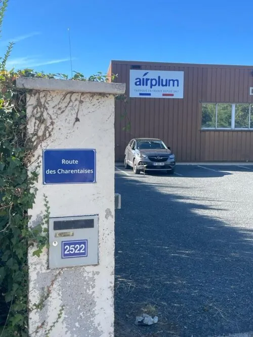 Usine avec enseigne Airplum derrière boite aux lettres avec panneau nom de rue de l’adresse